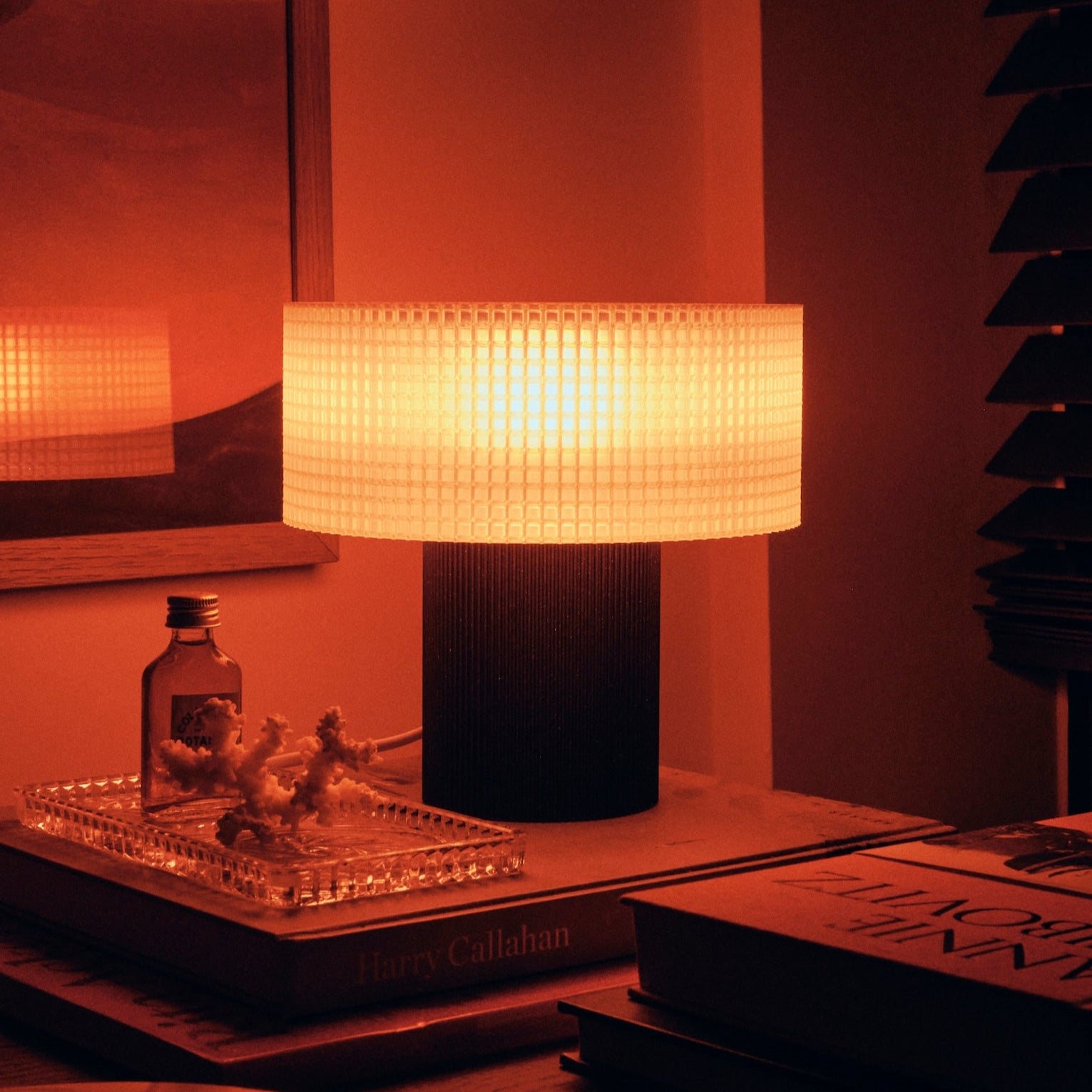 Dimly lit room with a table lamp and books on a wooden surface.